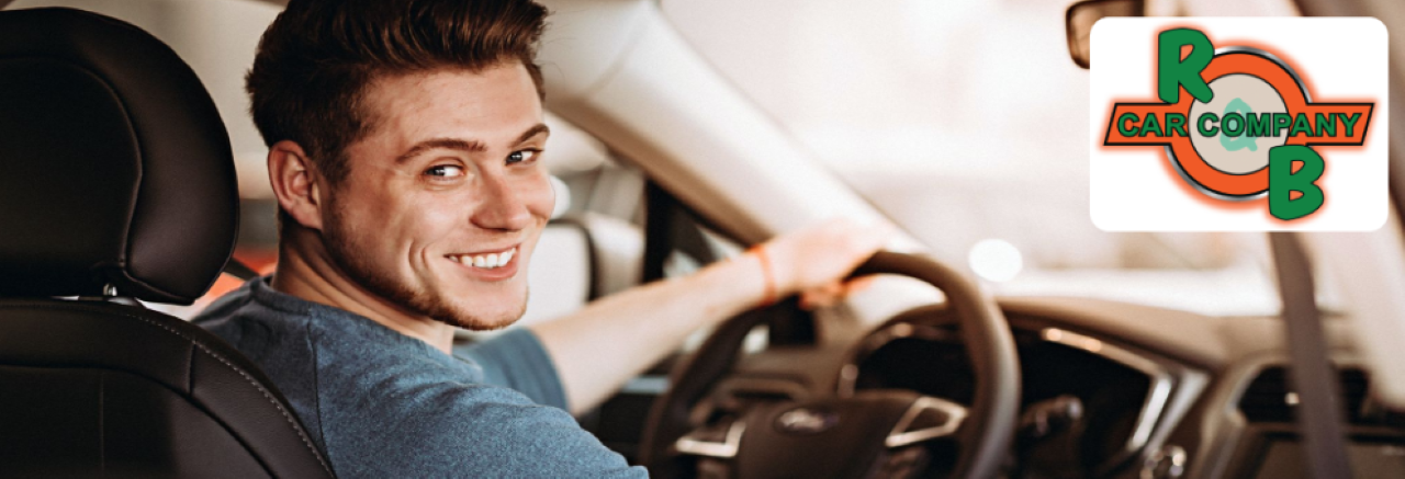 A happy customer test-driving a car from the R&B Car Company lot. The customer is smiling and engaged, enjoying the experience.